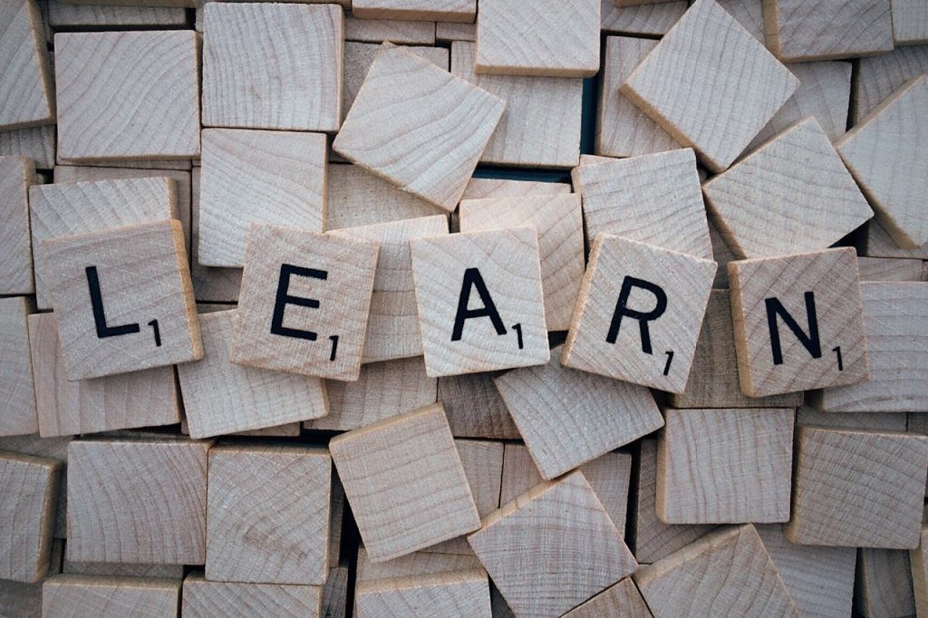 pexels-photo-247819 Wooden letter tiles arranged to spell 'learn' on a background of scattered tiles.